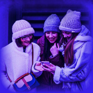 Das Bild zeigt eine Gruppe junger Leute, welche in Winterkleidung auf ein Handy schauen.