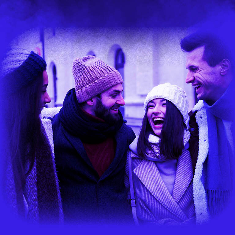 Das Bild zeigt eine Gruppe junger Leute, welche in Winterkleidung auf ein Handy schauen.