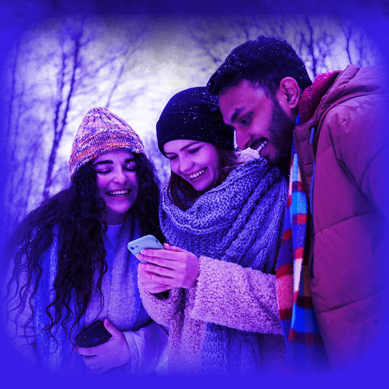 Das Bild zeigt eine Gruppe junger Leute, welche in Winterkleidung auf ein Handy schauen.