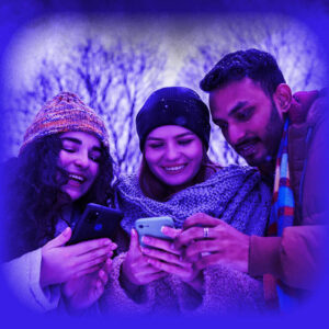 Das Bild zeigt eine Gruppe junger Leute, welche in Winterkleidung auf ein Handy schauen.