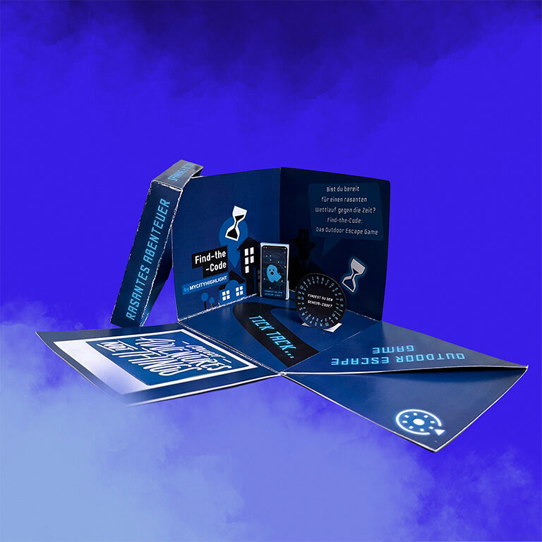 Fertig gebastelte DIY-Explosions-Geschenkbox von Find-the-Code, geöffnet mit sichtbaren Fächern, liebevollen Details und Platz für den Gutschein, auf Rauchhintergrund.